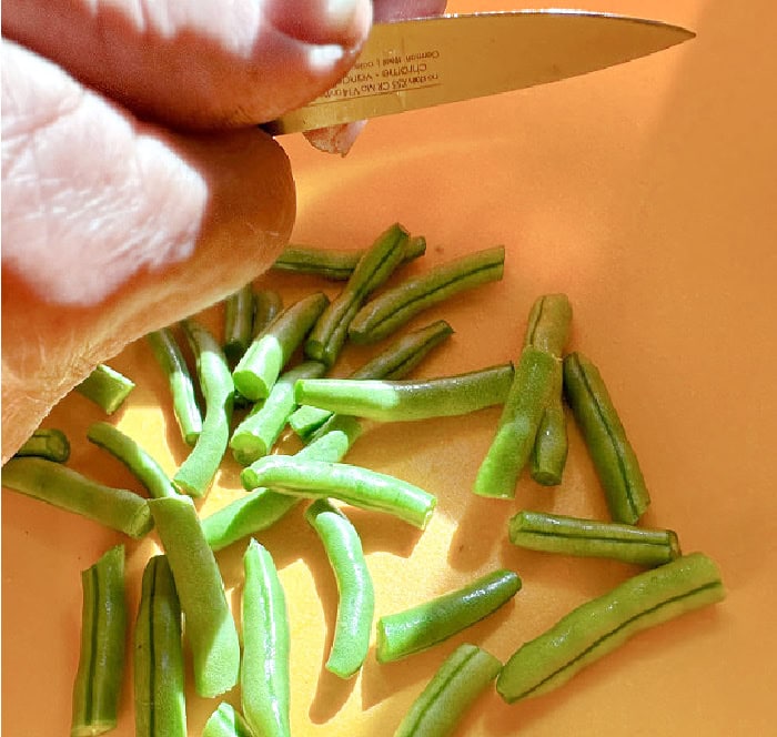 Fresh green beans are being trimmed and cut into pieces before pressure canning.