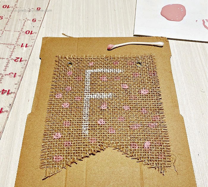 Painting the letter F and pink dots on a DIY fall burlap banner.