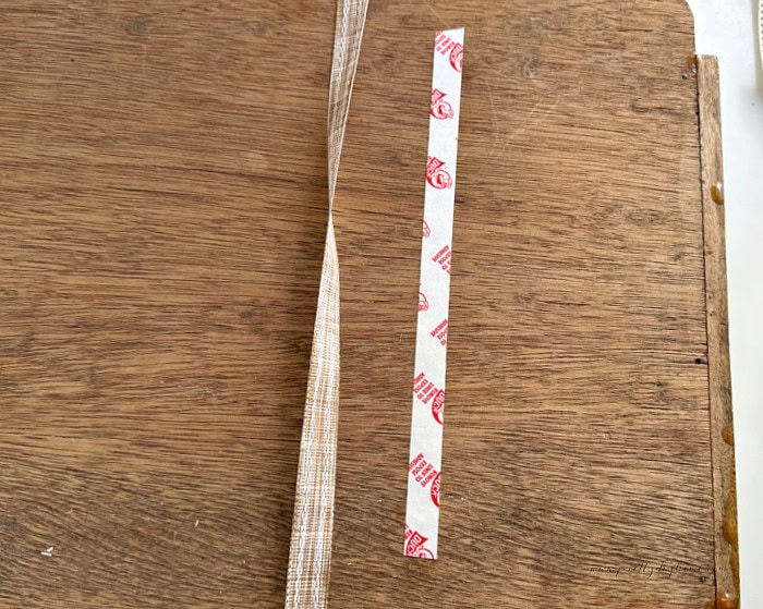 Double-sided tape applied to the back of a vintage wood tray to hold ribbon securely in place.