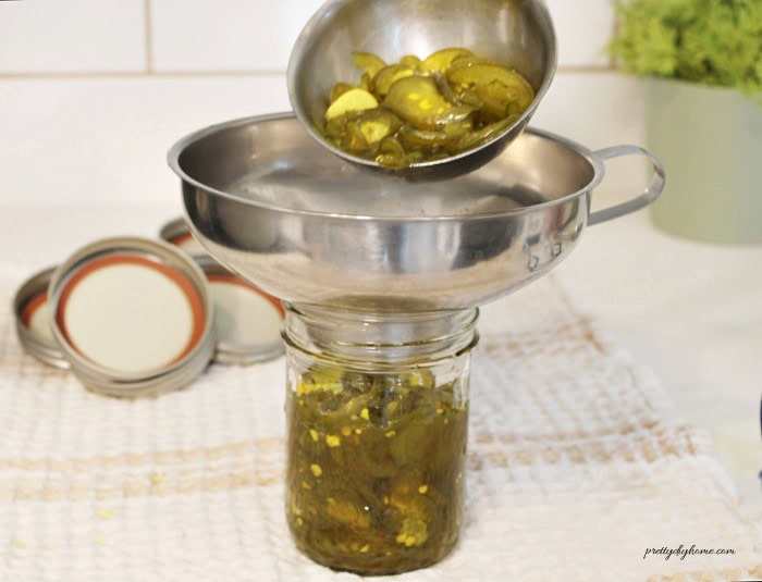 Filling half-pint jars with cowboy candy jalapeños and sweet pickling brine.