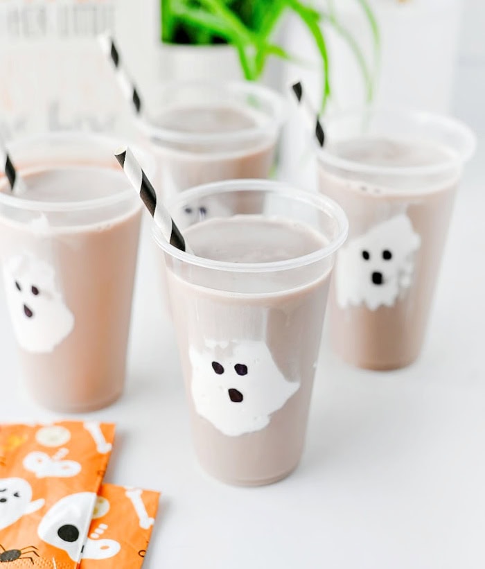Ghost chocolate milk with marshmallow fluff ghosts showing through clear cups.