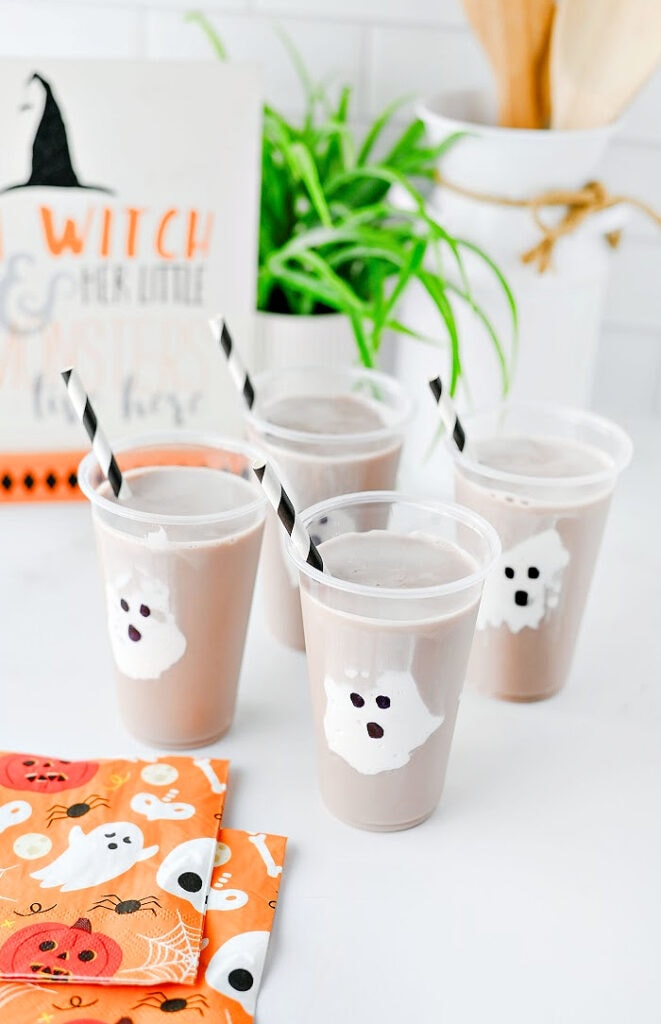 Halloween ghost chocolate milk drinks for kids with marshmallow fluff ghosts in clear cups.