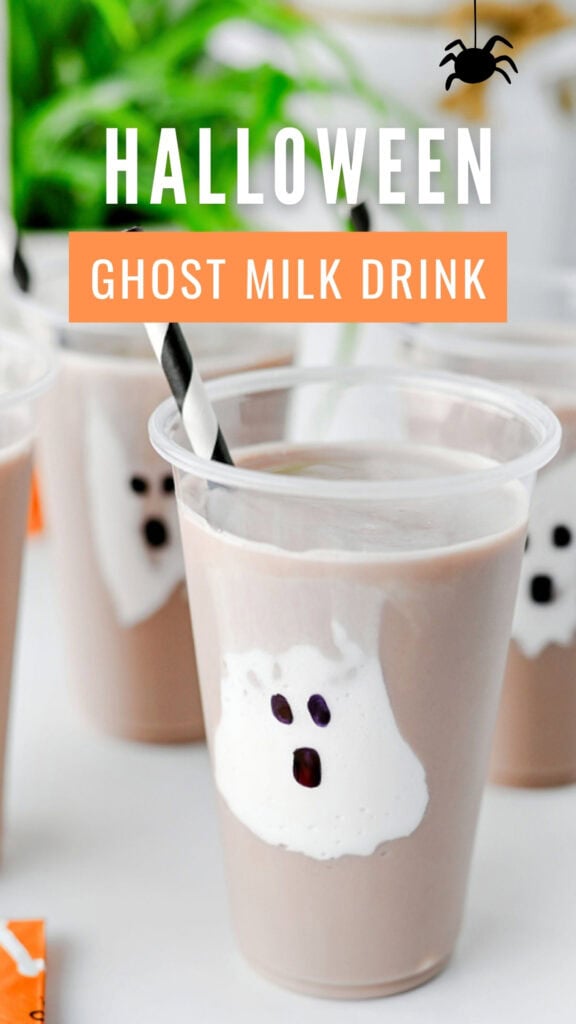 Ghost chocolate milk in a clear cup with a marshmallow fluff ghost, striped straw, and Halloween napkins.