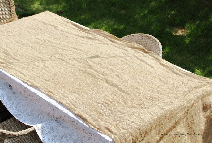 Burlap fabric spread flat over an outdoor table to air dry in the fresh air.
