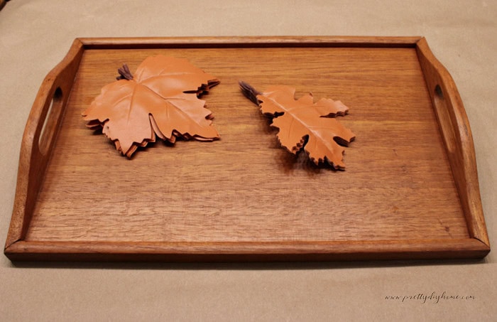 Orange faux fall leaves before being painted cream for a vintage wood tray makeover.