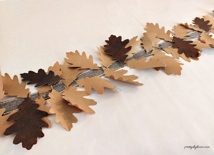 Dark brown paper oak leaves are scattered along the brown paper leaf garland to form the second layer and add contrast.