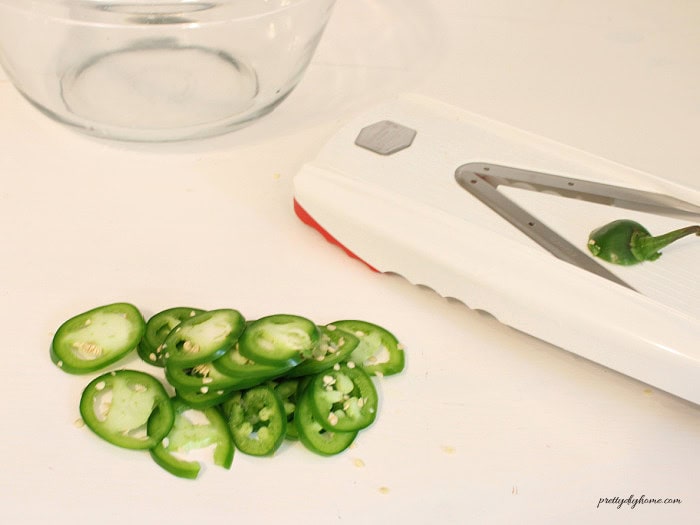 Slicing jalapenos into 1/4 inch rings with a mandoline for cowboy candy.