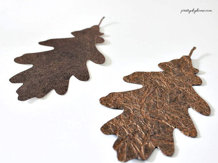 Two brown paper oak leaves showing the different smooth and crinkled textures used for the DIY leaf garland.