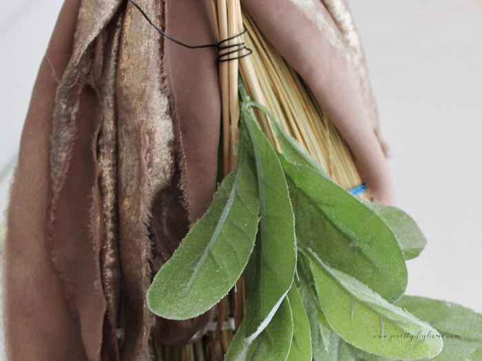 Floral wire wrapped around the broomcorn and wheat bundle to create a secure base for decorating a cinnamon broom.