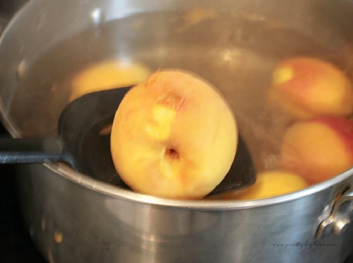 Peach being lifted from boiling water while blanching peaches for homemade peach salsa.