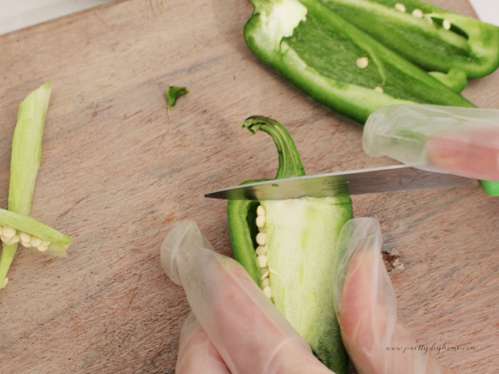 Wearing kitchen gloves while chopping jalapeño peppers and removing the seeds for peach salsa.