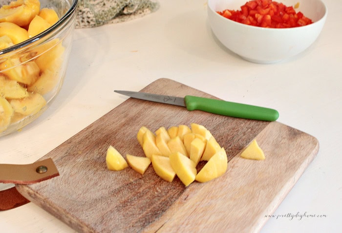 Chopped fresh peaches on a cutting board while preparing homemade peach salsa.