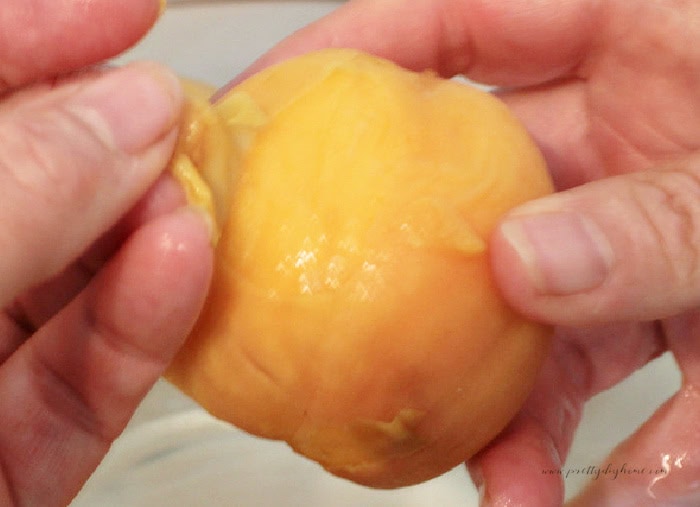 Peeling the skin from a blanched peach by hand for homemade peach salsa.