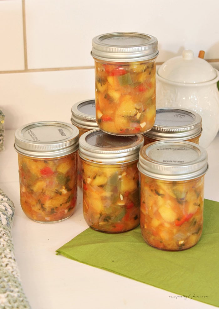 Stacked jars of homemade canned peach salsa cooling after water bath canning.