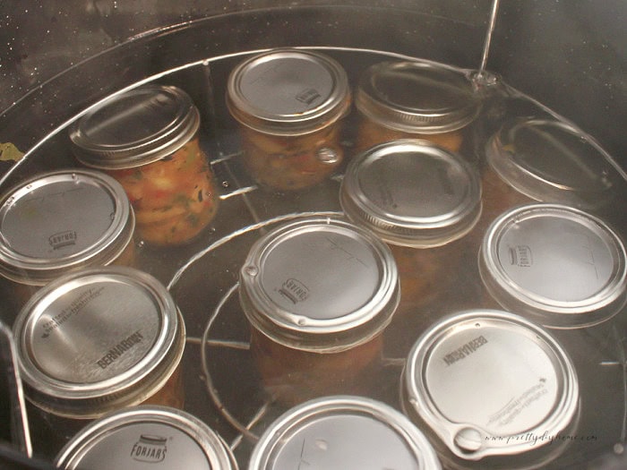 Half-pint jars of peach salsa submerged in a water bath canner for processing.