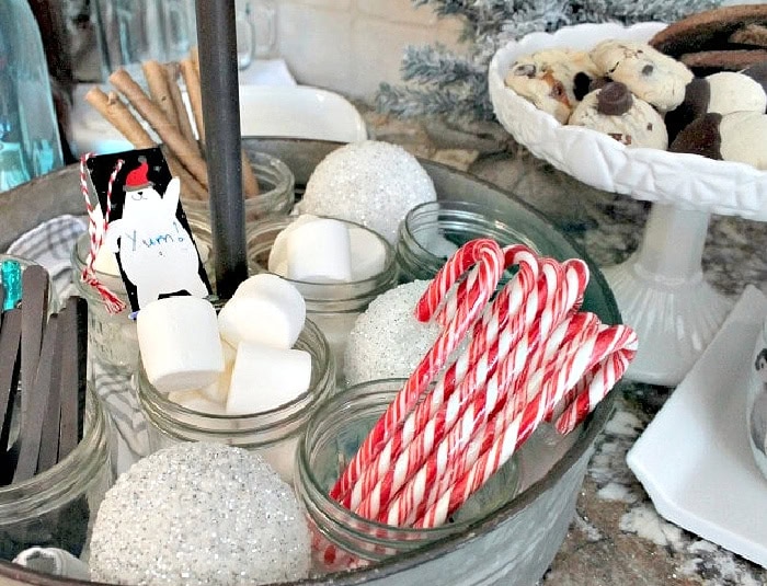 Christmas hot chocolate bar with marshmallows, candy canes, cinnamon sticks, and chocolate stirrers.