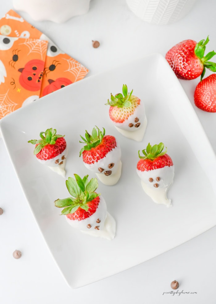 Cute Halloween strawberry ghosts lined up on a white serving tray.