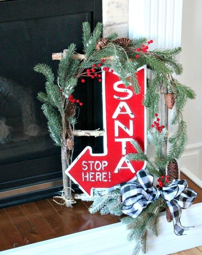 DIY birch twig Christmas wreath with greenery, berries, ribbon, and a Santa sign.