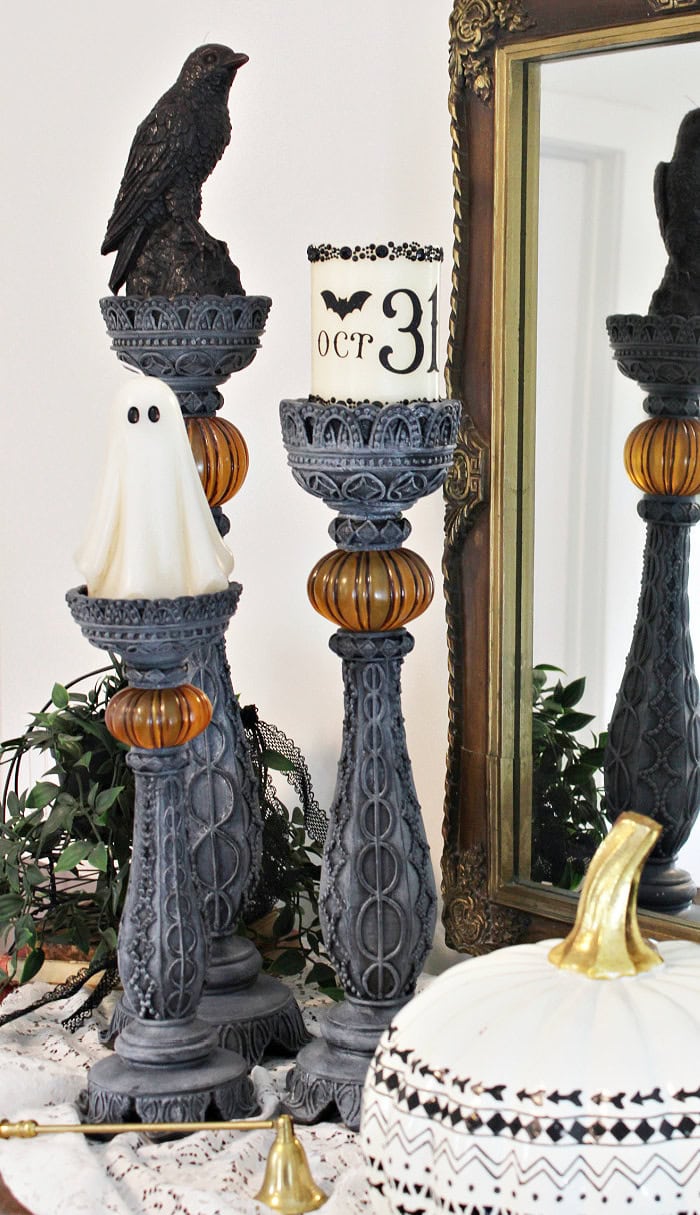 DIY Halloween candlesticks styled with a ghost candle, black crow candle, OCT 31 pillar candle, pumpkin, and vintage candle snuffer.
