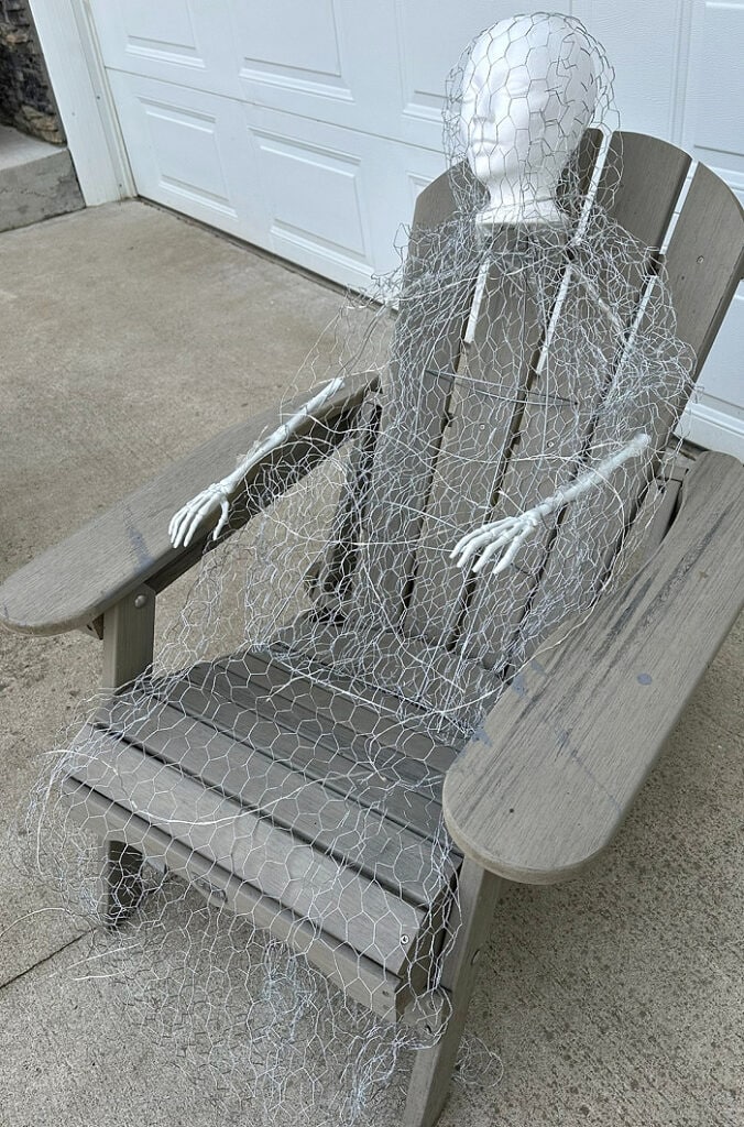 The completed wire frame for a DIY Halloween ghost sits in an Adirondack chair before the fabric is added.