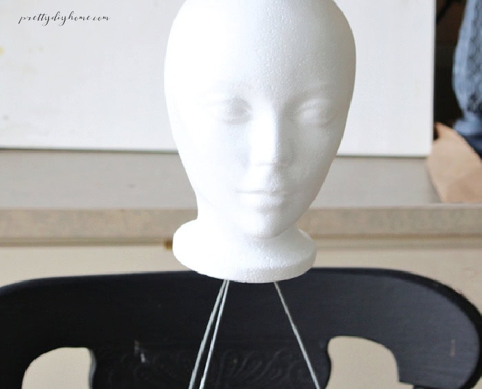 A styrofoam head is attached to the top of the wire frame for a DIY Halloween ghost.