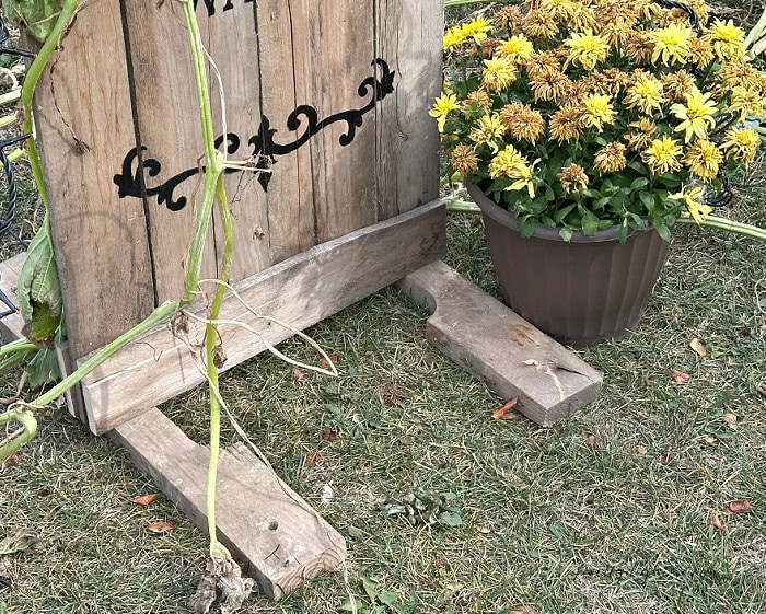 Wooden 2×4 base supporting a DIY pallet Halloween gravestone outdoors.