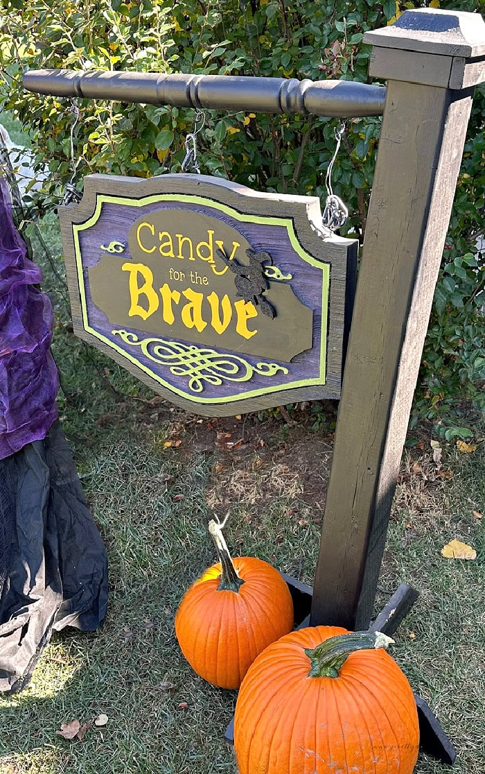 DIY outdoor Halloween sign reading Candy for the Brave with pumpkins beside the wooden post.