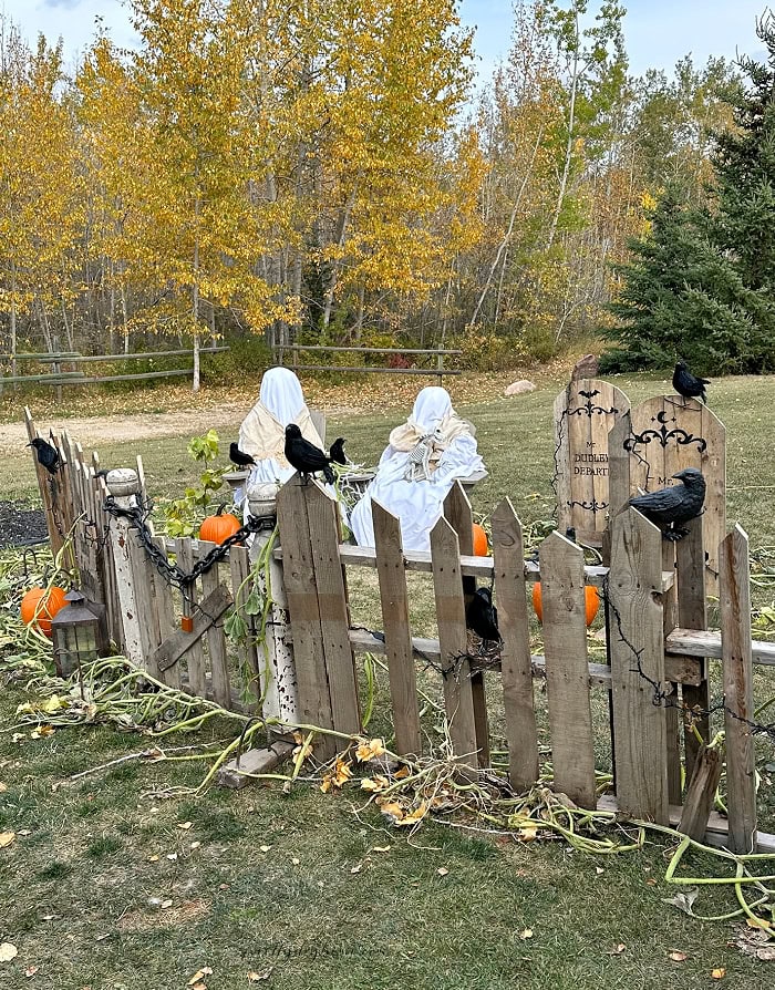 DIY outdoor Halloween yard display with pallet fence, ghosts and wooden gravestones.