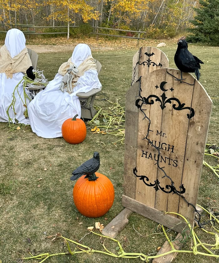 DIY pallet Halloween gravestone with crow, pumpkin and outdoor ghost decorations.