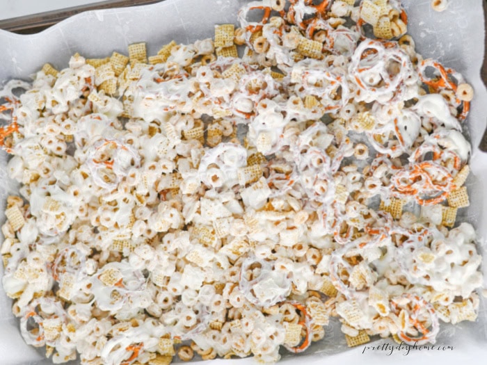 Melted white chocolate coating Rice Chex, Honey Nut Cheerios, and pretzels for an easy Halloween party snack mix.