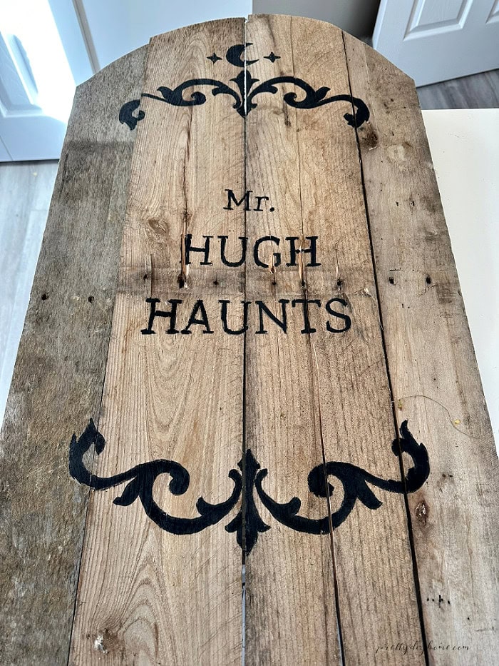 Finished Mr. Hugh Haunts lettering and decorative stencils painted on a pallet wood Halloween gravestone.