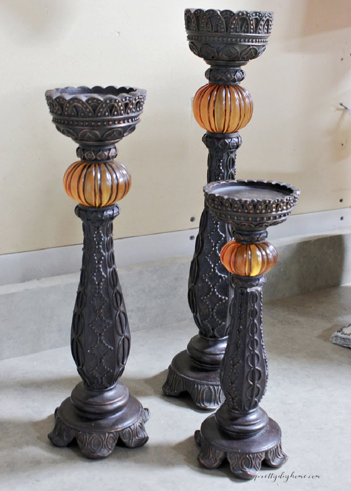 Three large 1970s style candlesticks before their Halloween makeover, with dark carved details and orange center sections.