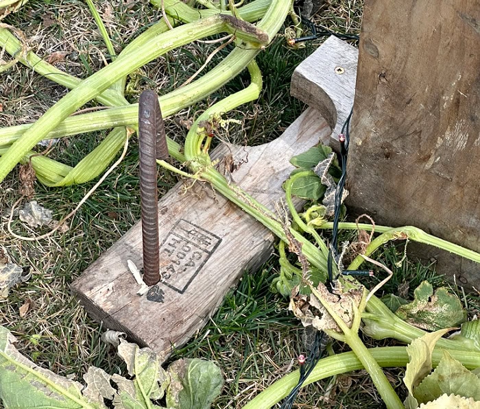 Rebar driven through a wood base support to secure a DIY pallet Halloween gravestone in the ground.