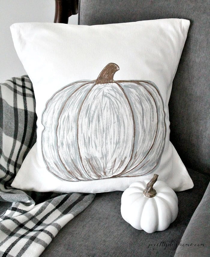 Hand painted pumpkin pillow in neutral grey and brown with a white pumpkin for fall decor.