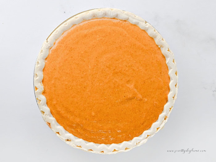 Pumpkin filling spread over the cream cheese layer in a layered pumpkin pie cheesecake.