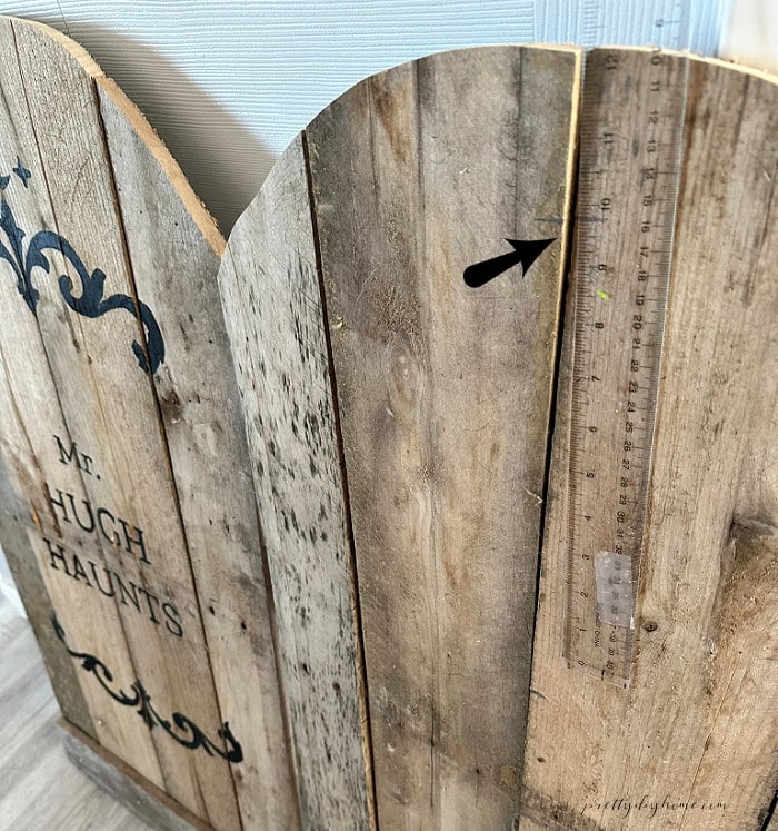 Using the finished pallet wood gravestone as a guide to measure matching DIY Halloween gravestones.