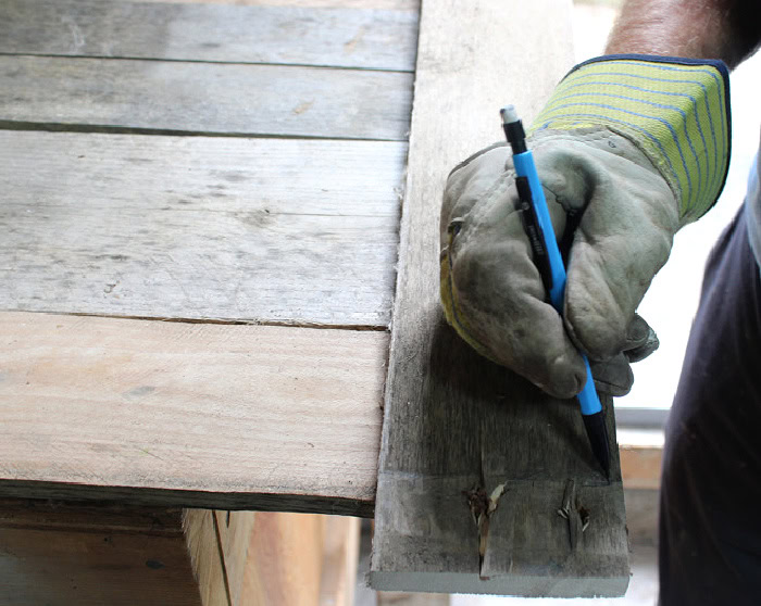 Measuring pallet wood cross pieces for a DIY Halloween gravestone.