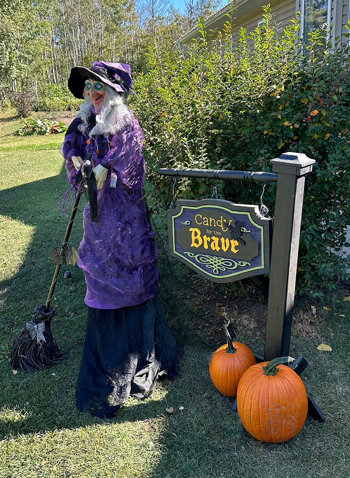 Outdoor DIY Halloween yard sign with Candy for the Brave lettering, witch, and pumpkins.