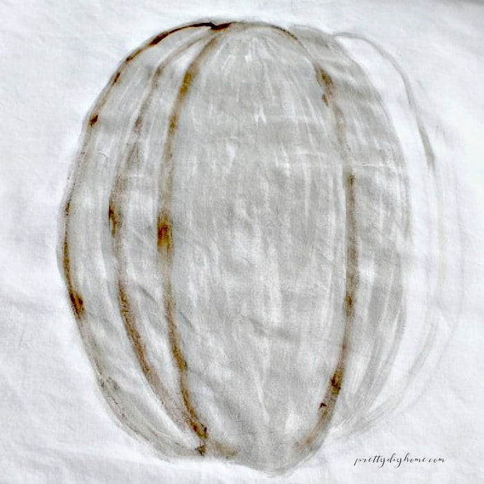 Painted pumpkin pillow showing grey and brown shading on the pumpkin sections.