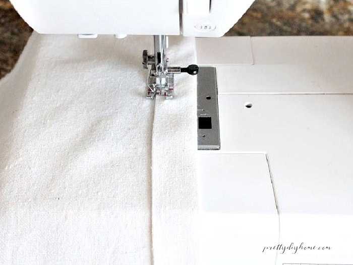 Sewing a folded hem on the back piece of an envelope pillow cover.