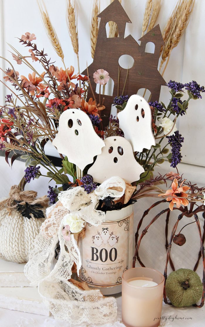 Vintage ghost Halloween centerpiece with wooden ghosts, haunted house, flowers, lace, and BOO label.