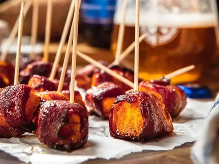 Bacon-wrapped sweet potato bites baked until golden and caramelized, served with toothpicks for easy Christmas party appetizers.