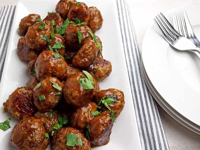Chicken Marsala meatballs coated in a rich, savoury mushroom sauce and garnished with fresh parsley on a white serving platter.