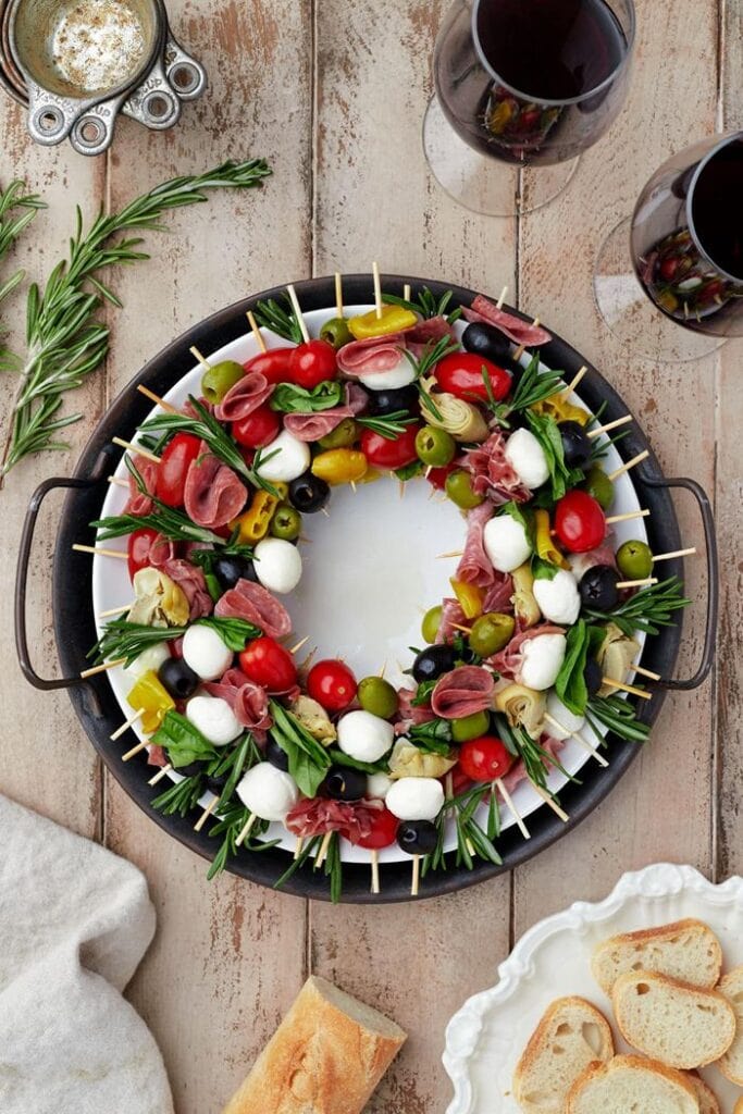 Christmas antipasto charcuterie wreath arranged with salami, cheese, olives, cherry tomatoes, and fresh rosemary on a round serving platter.
