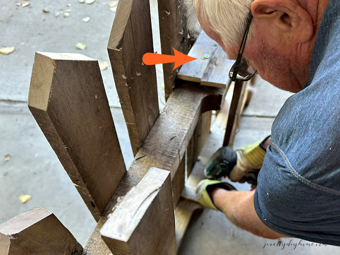 Connecting pallet fence sections with scrap wood pieces for a DIY Halloween fence.