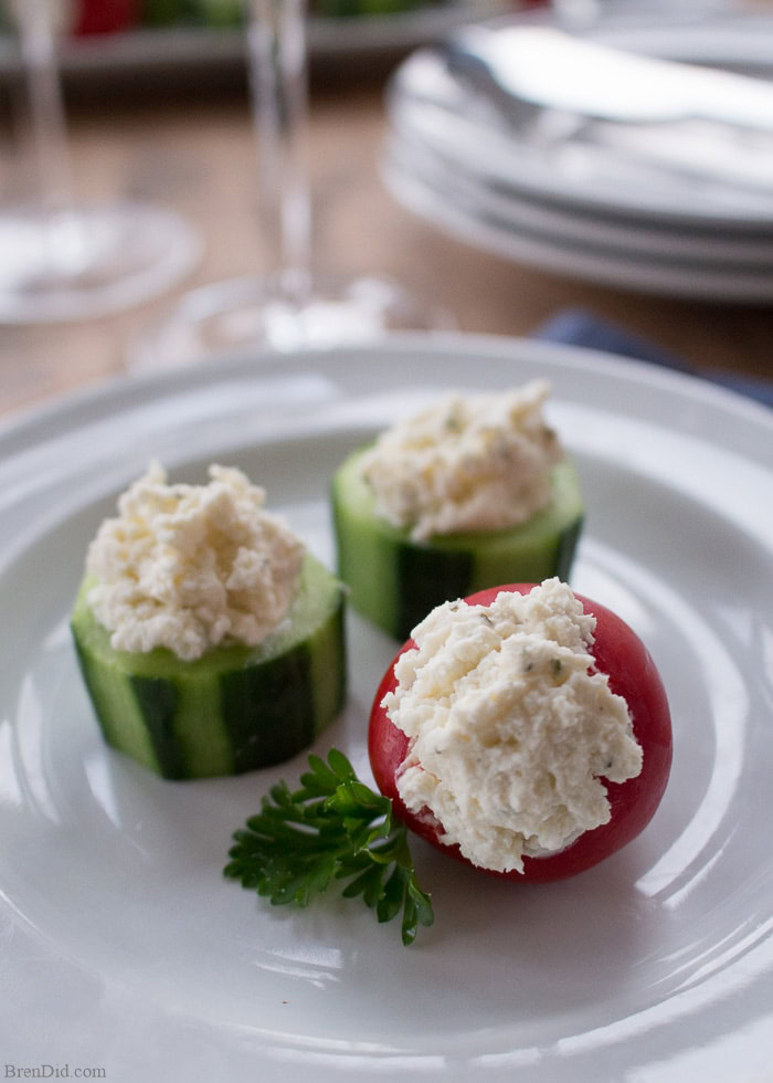 Cucumber cups and a red cherry pepper filled with a creamy herbed cheese mixture, served on a white plate.