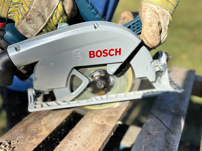 Cutting pointed pallet fence pickets with a circular saw for a DIY Halloween fence.