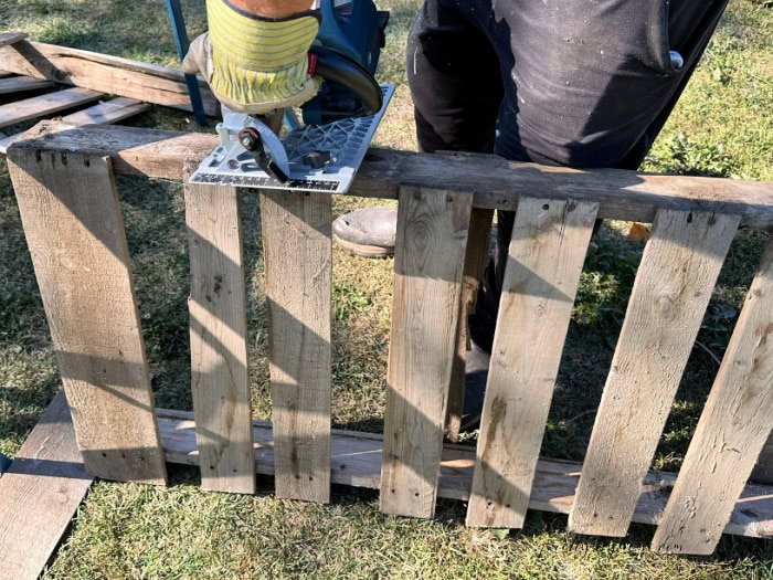 Cutting a pallet gate to size with a circular saw for a DIY Halloween fence.