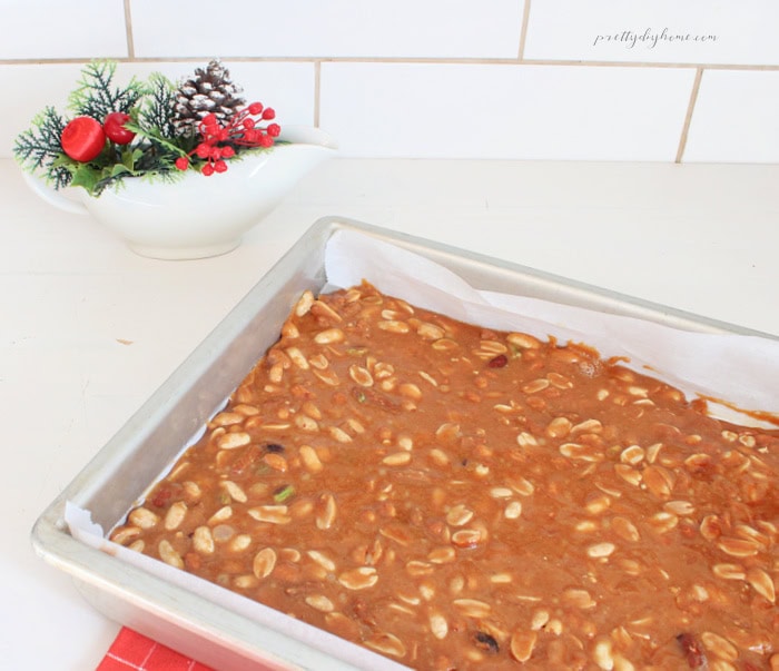 Homemade mixed nut brittle cooling on a parchment-lined baking sheet, showing golden peanut brittle filled with assorted nuts.