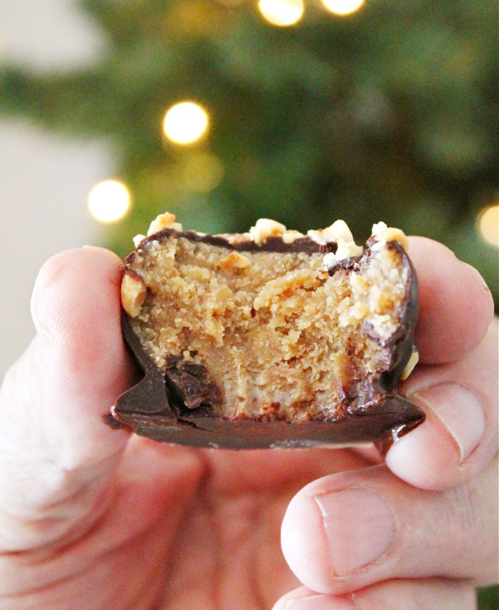 Hand holding a chocolate coated Nutter Butter peanut butter ball with a bite taken out, showing the peanut butter filling.